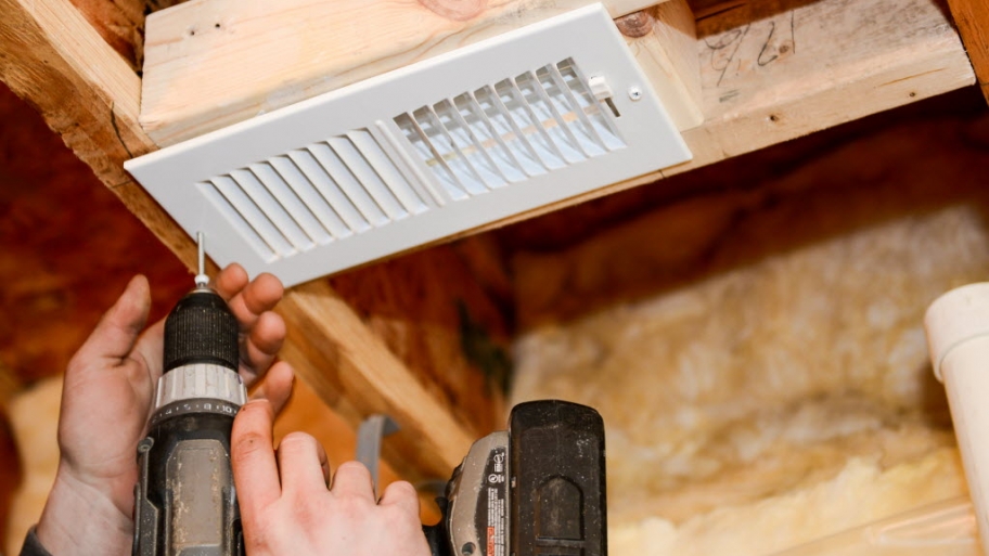 Worker installing vent with drill